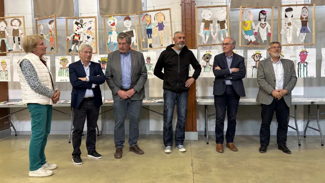 Competition organizers and jury members standing in front of a wall of children's exhibited artworks