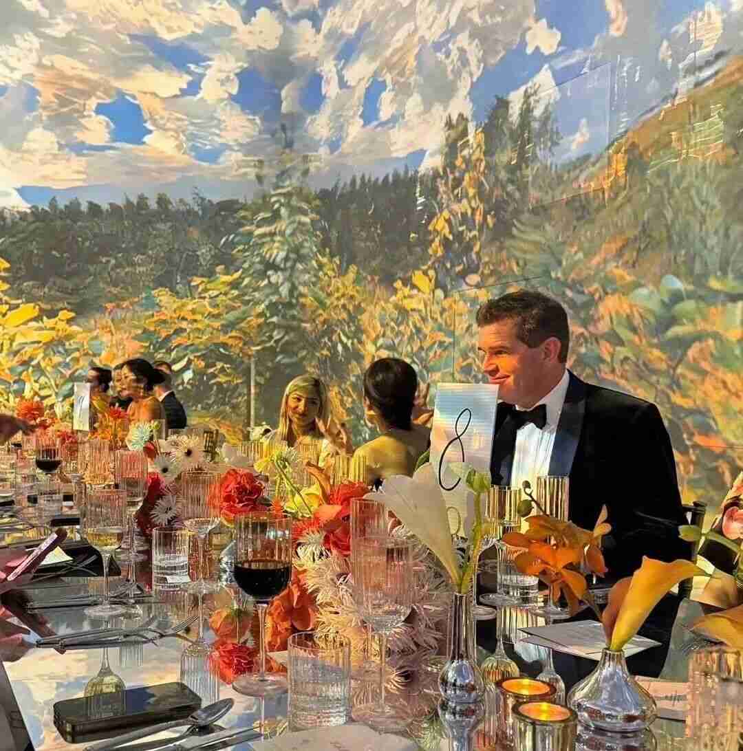 Formal dinner event with an immersive painted landscape mural backdrop