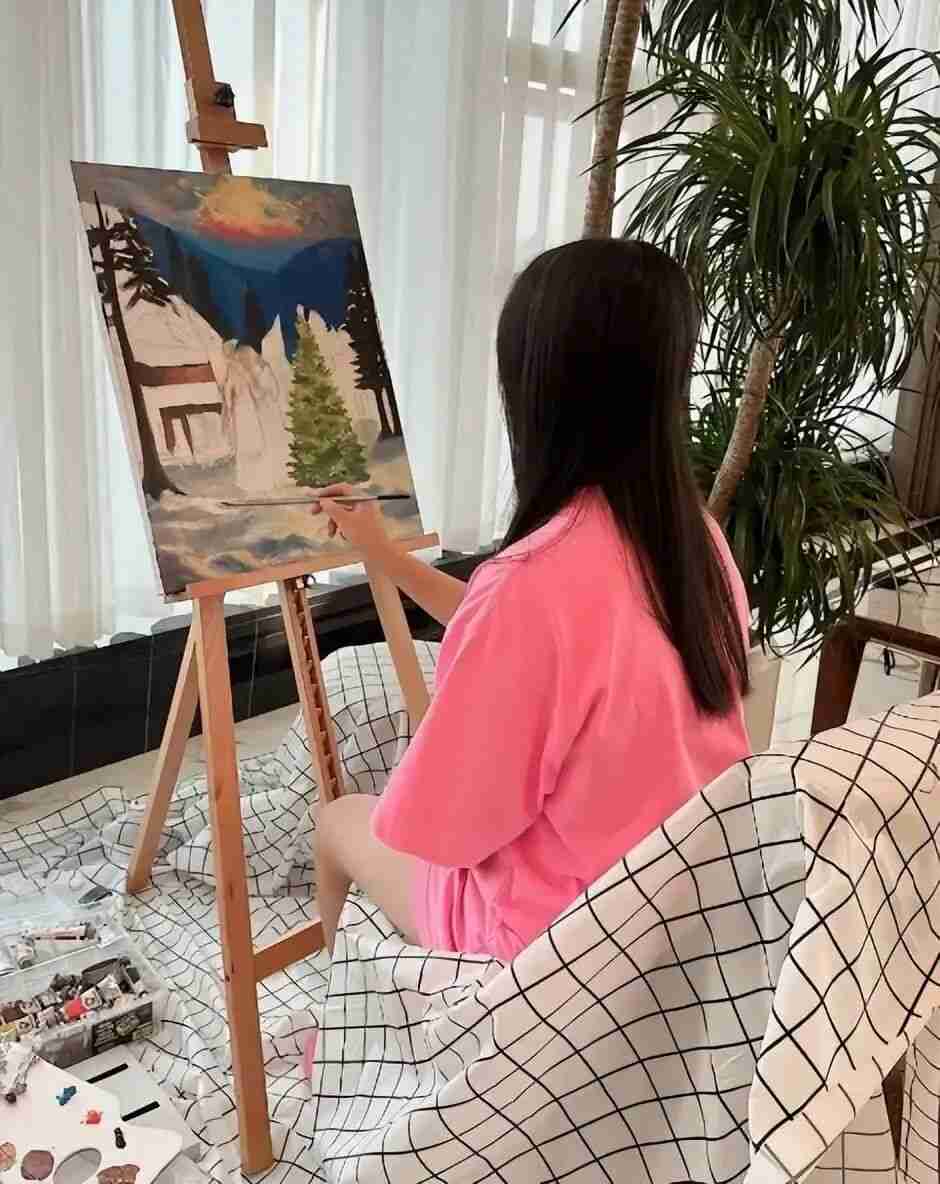 Young girl painting a winter landscape on canvas at an easel