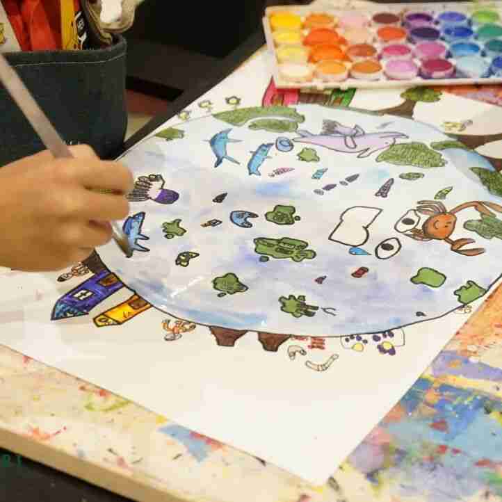 Student at TreeArt painting a detailed watercolor scene with dolphins, a deer, and trees