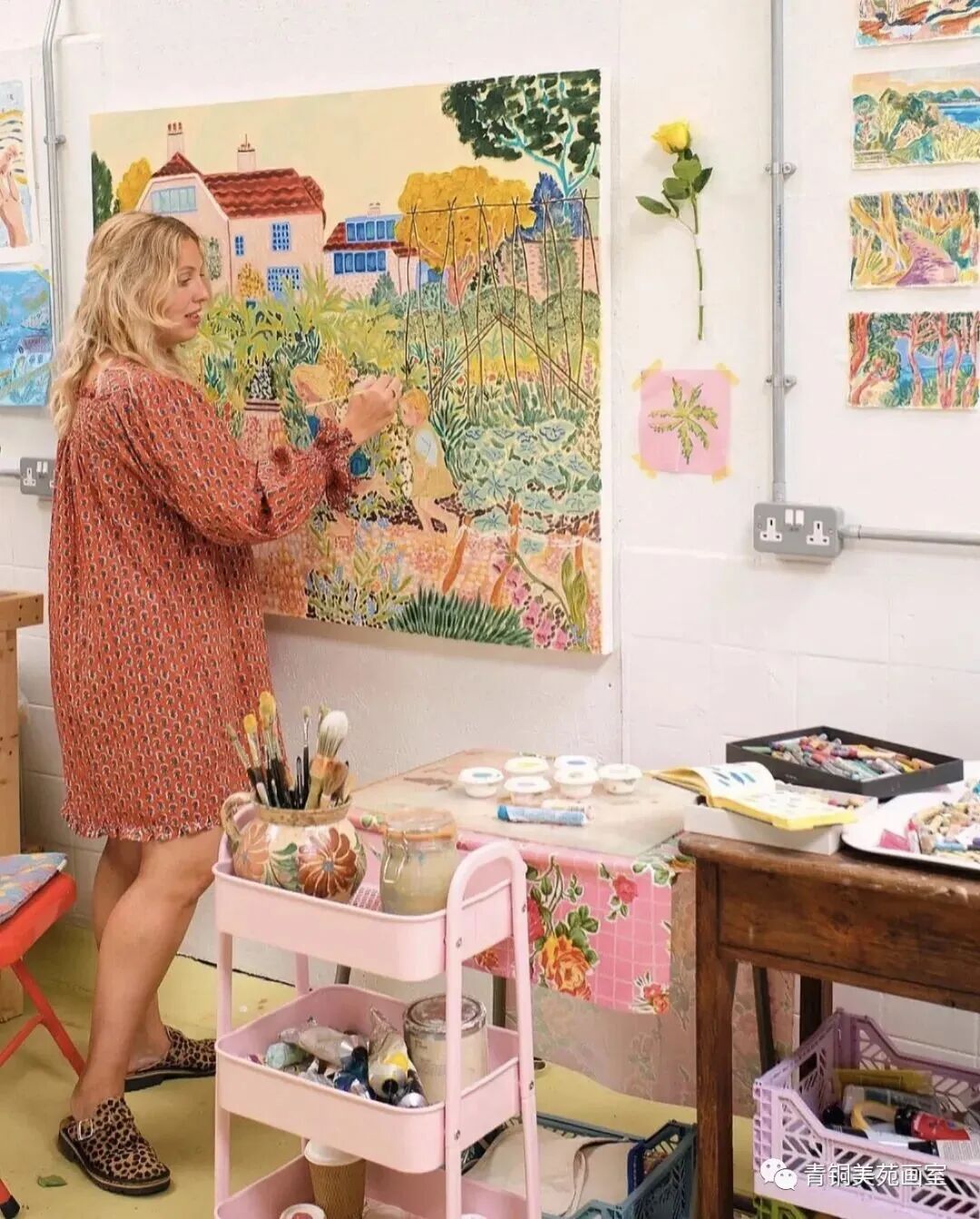 Camilla Perkins painting a colorful garden scene in her home studio, surrounded by art supplies and her artworks