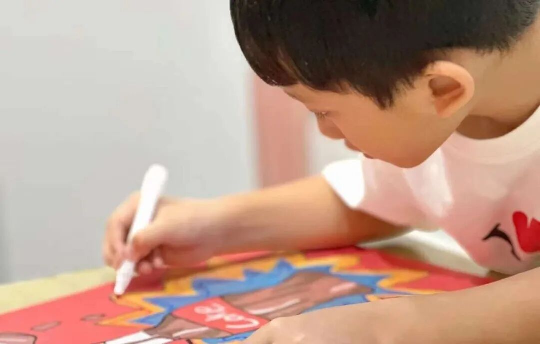 A young boy draws with a marker on a colourful picture
