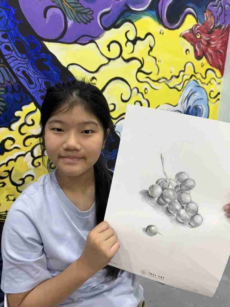 TreeArt student smiling while holding a detailed pencil drawing of grapes