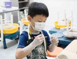 TreeArt student in a mask focused on a pottery project