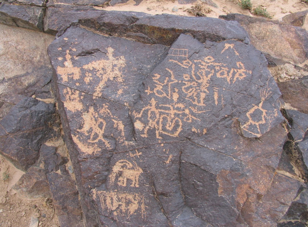 Ancient petroglyphs of human and animal figures carved into a rock surface