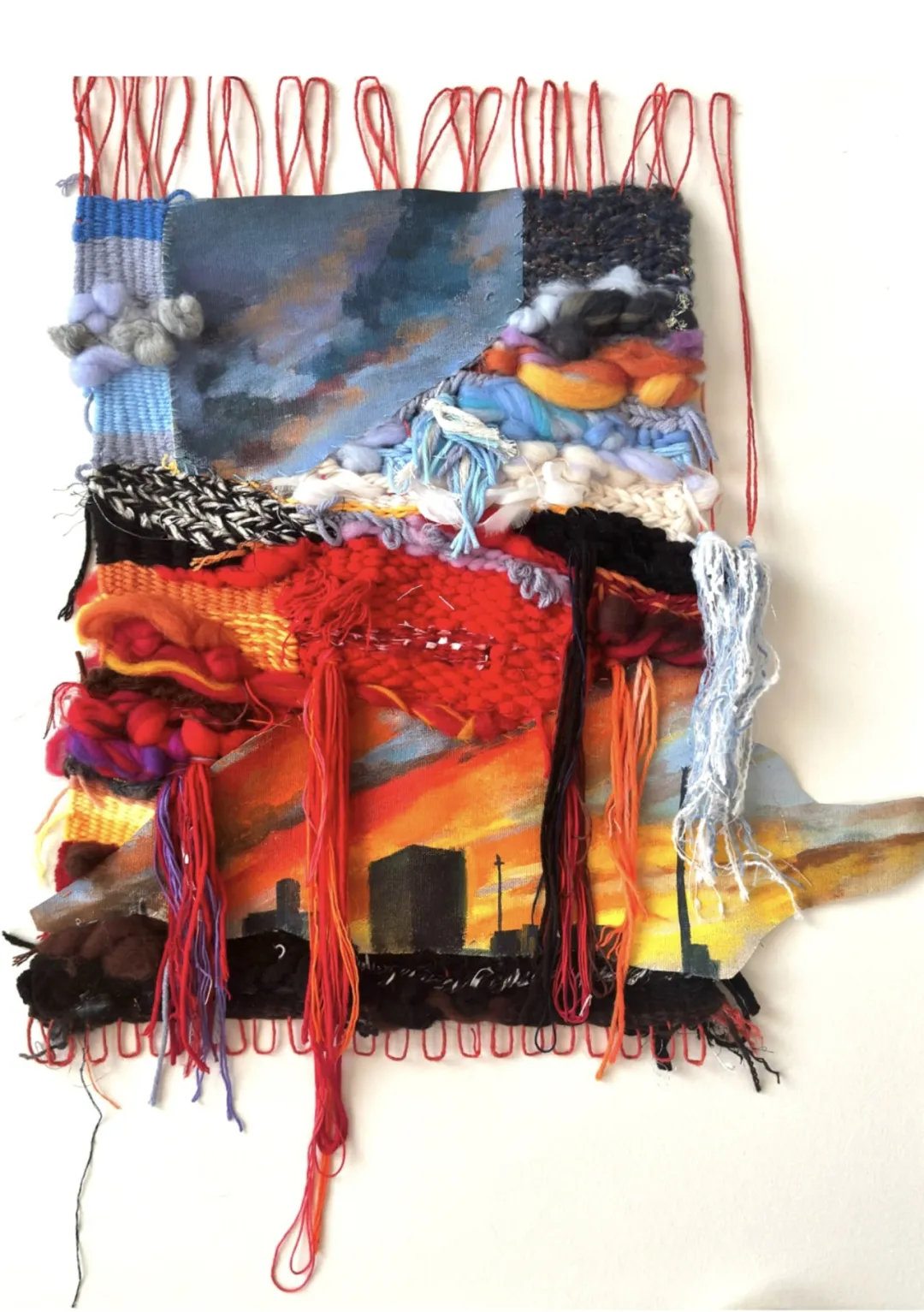 Sunset by 陈思睿, a full view of a mixed-media woven textile artwork combining a painted city skyline with layered fiber and yarn, submitted by 朝阳凯文艺术中学