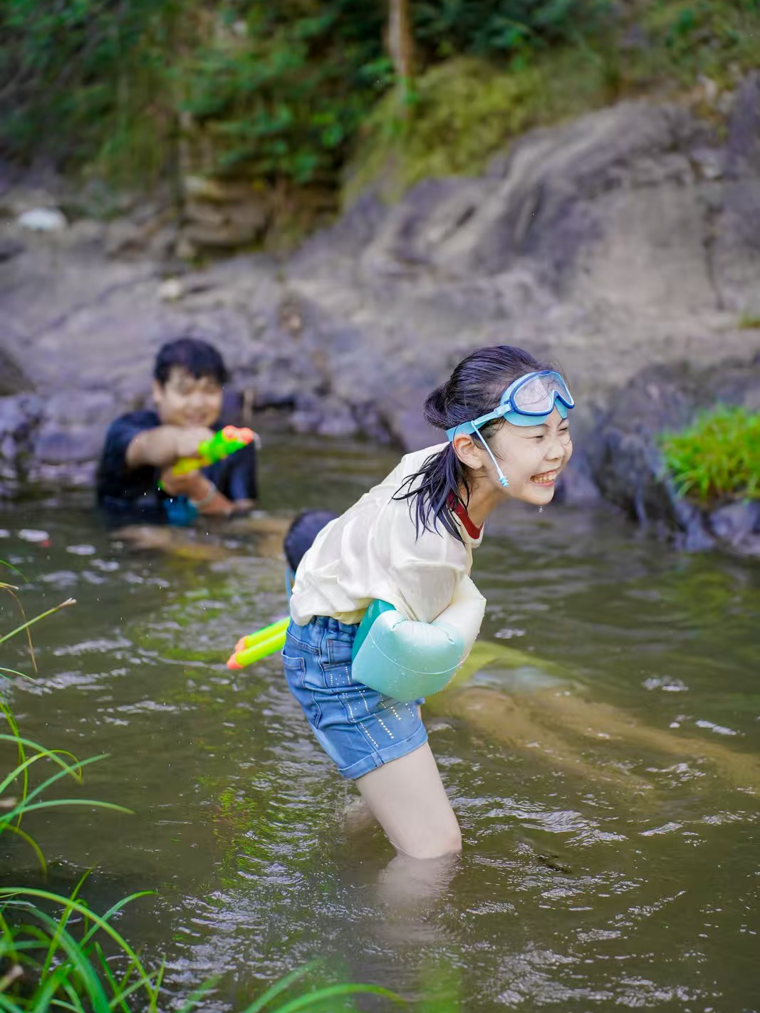 Children enjoying water play surrounded by green hills