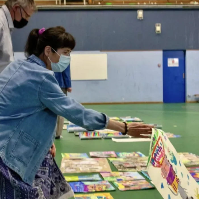 A juror selecting an artwork from the entries spread across the gymnasium floor