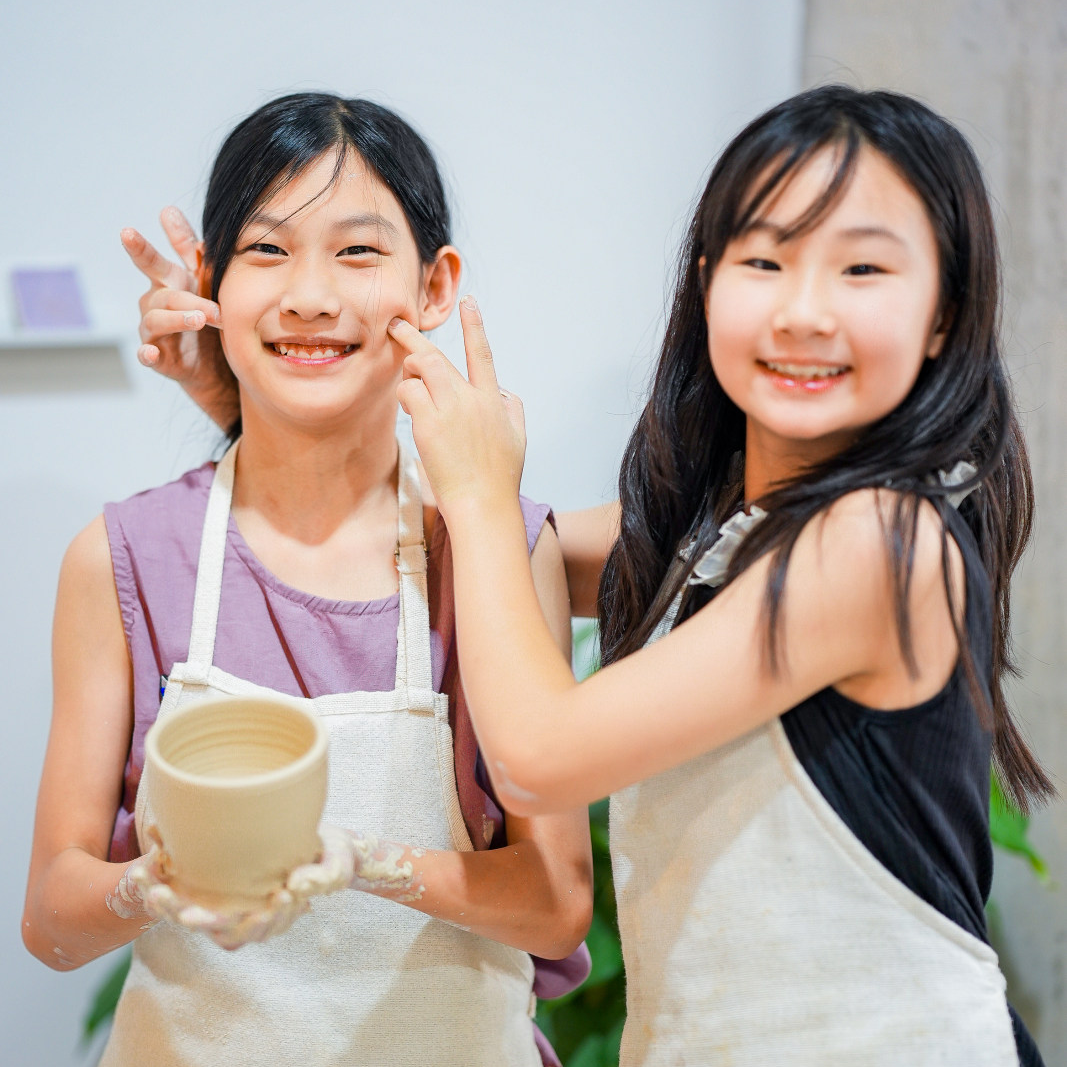 Child working clay on a pottery wheel during the throwing experience