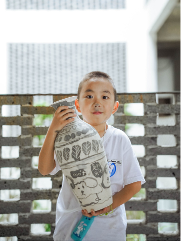 Child painting cobalt-blue designs onto ceramic bisque