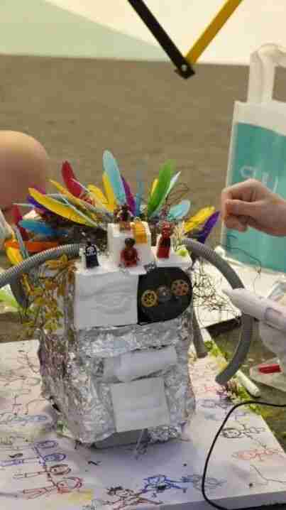 A robot sculpture made from recycled foil, gears and feathers, an example of ART TECH creative work