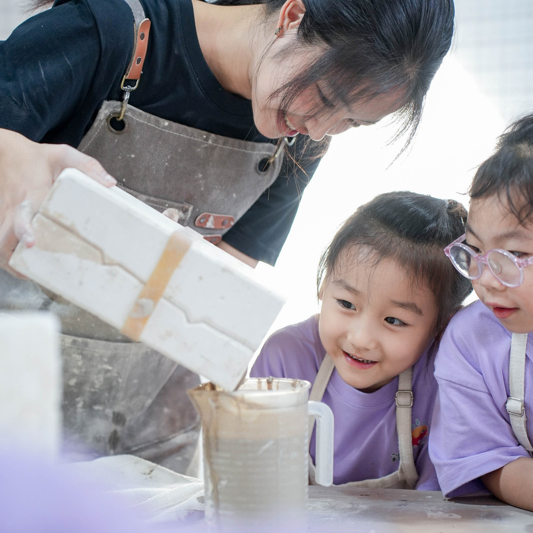 Children treading and working wet clay with bare feet