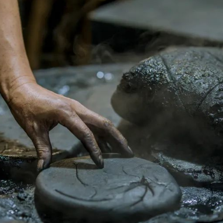 Child learning the gilding technique on a hand-shaped ink stick