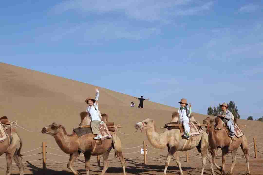Children riding camels across the dunes at Mingsha Mountain