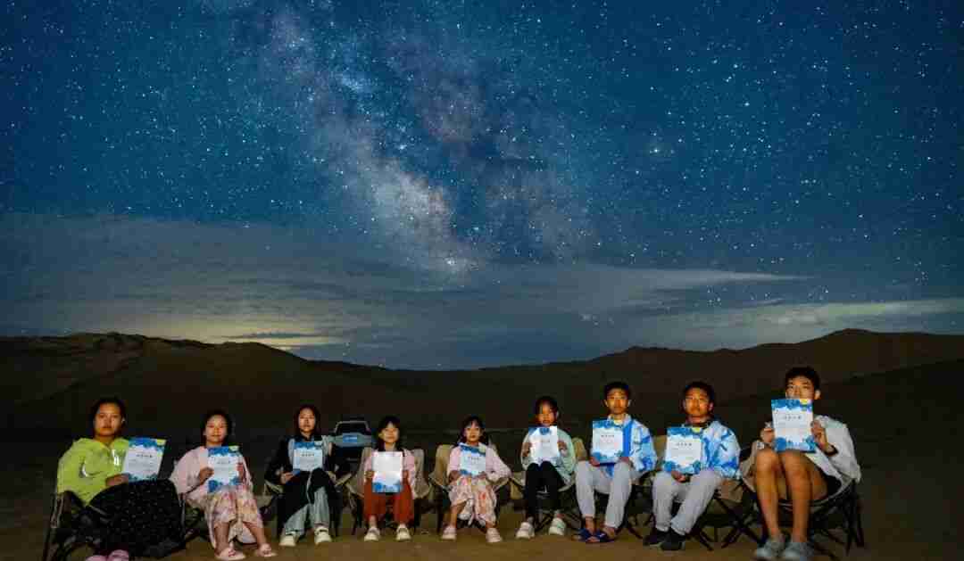 Children observing the night sky through a telescope in the desert