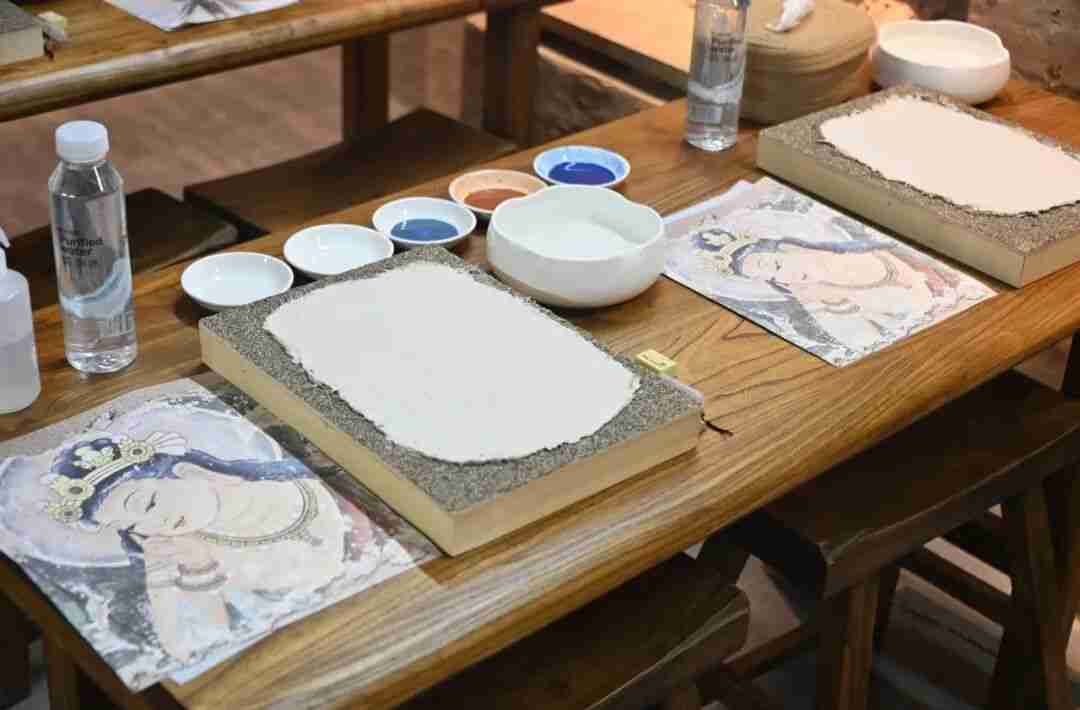 A child applying pigment to a handcrafted clay tablet