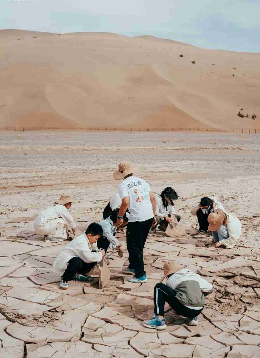 Children sifting five-colored sand in the desert