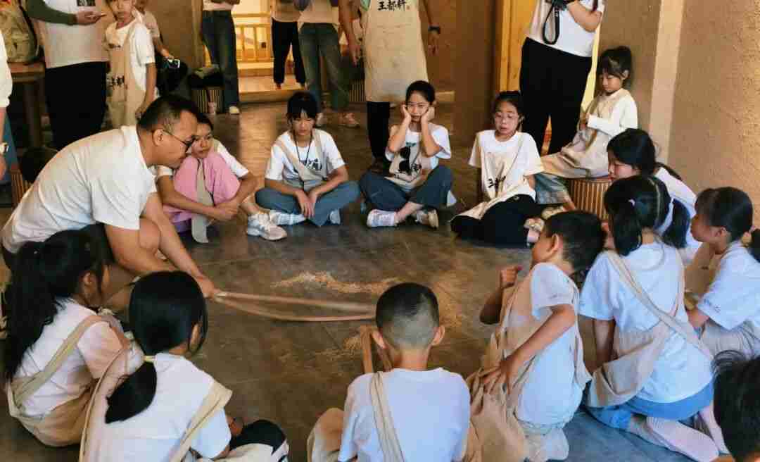 Children processing wheat straw and hemp fibers for the mud layer