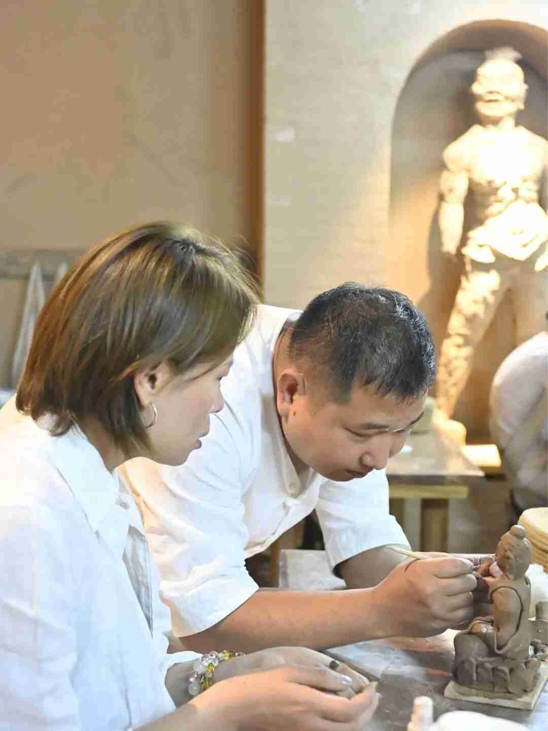 Children applying layers of clay over a wooden skeleton sculpture