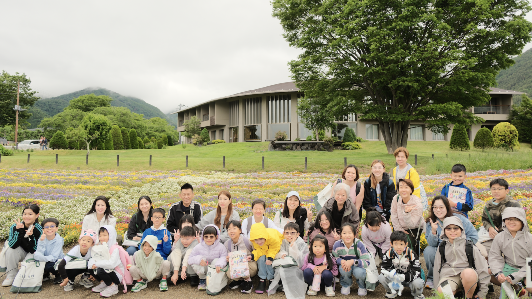 The summer tour group photographed in a flower field at the foot of the mountains