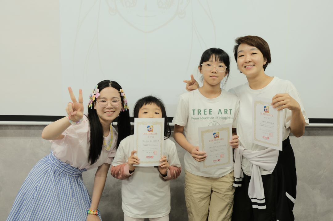 Children posing with their manga drawings and certificates at AMPS Anime School