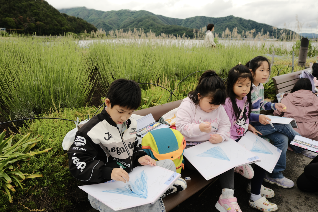 A child painting the view of Mount Fuji from the shores of Lake Kawaguchi