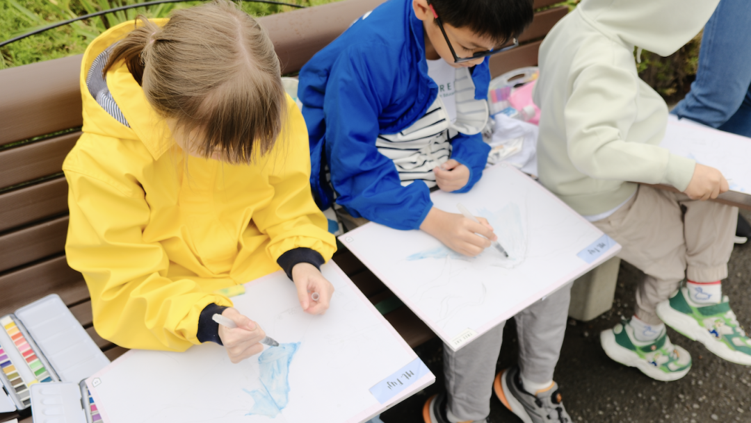 Children setting up their drawing boards beside Lake Kawaguchi with Mount Fuji in the distance