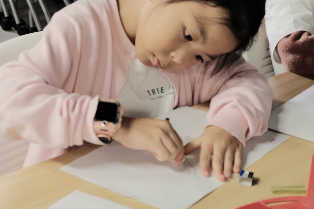 A child concentrating on a manga drawing exercise at AMPS Anime School